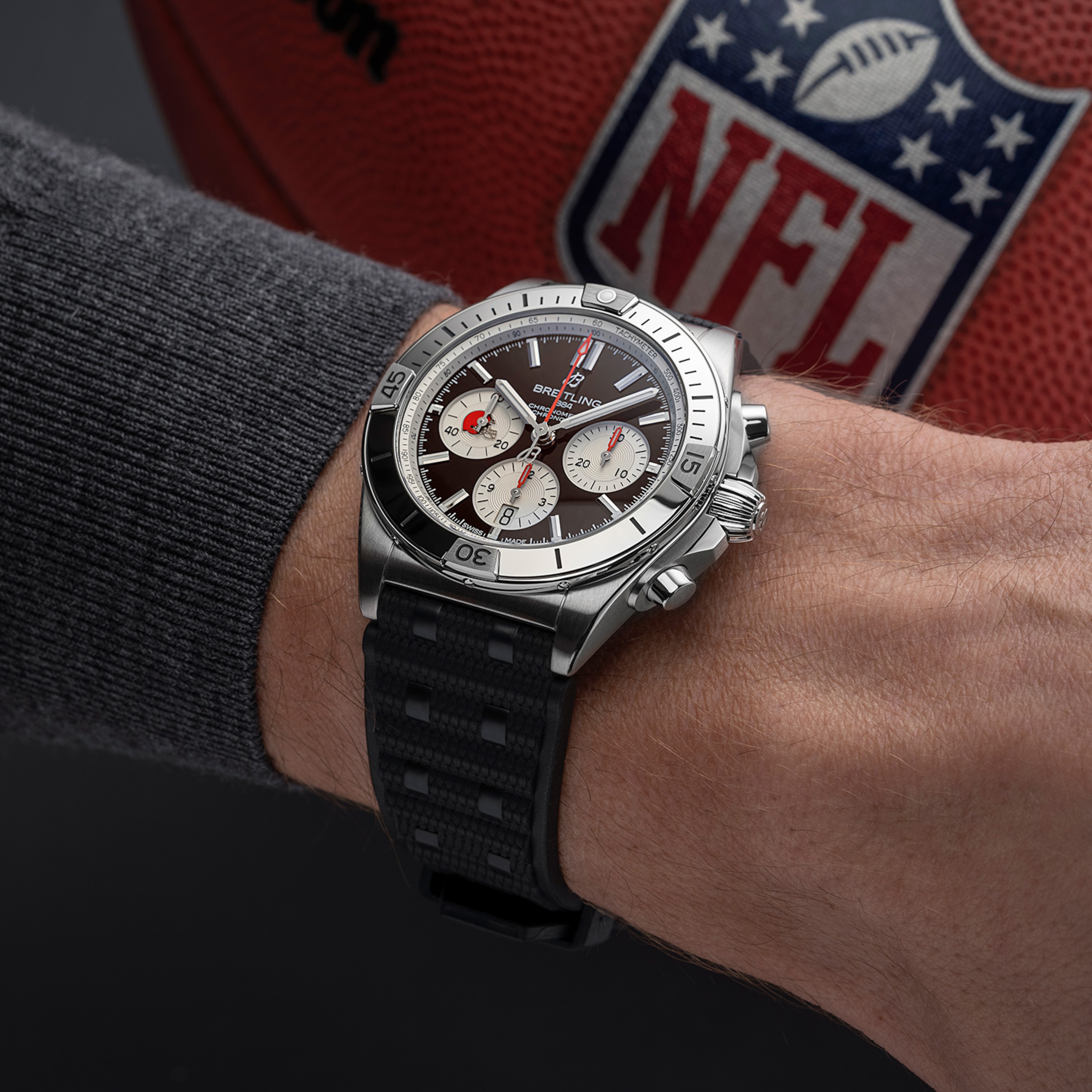 A watch from the limited NFL collection with a black dial on a glossy surface.