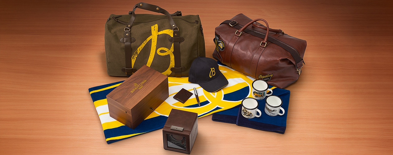 {generated} Breitling-Reisetaschen, Mütze, Tassen und Boxen auf Holzfläche arrangiert und die exklusiven Accessoires hervorhebend
