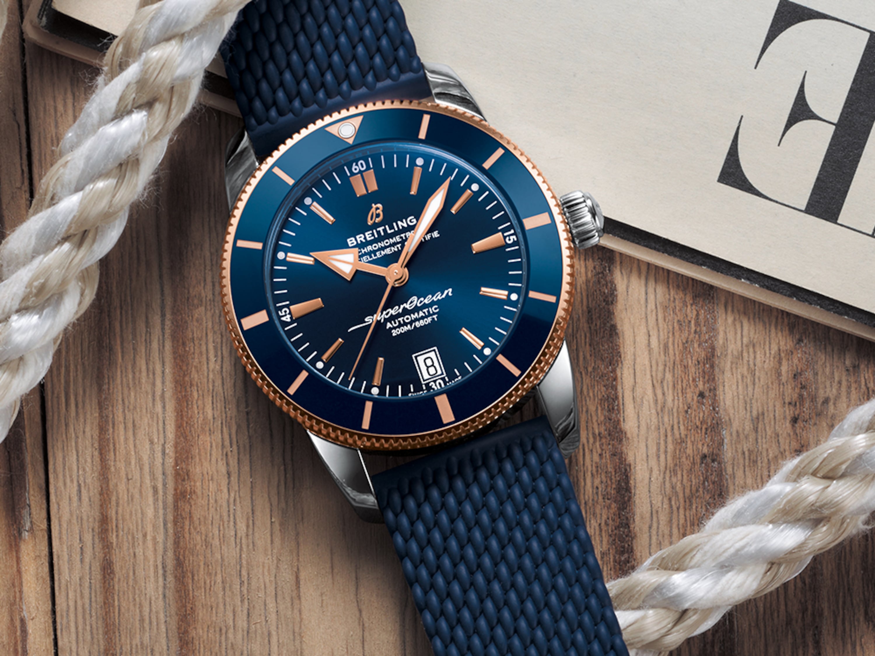 Un Superocean Heritage azul oscuro descansa sobre una mesa con una revista y una cuerda blanca.