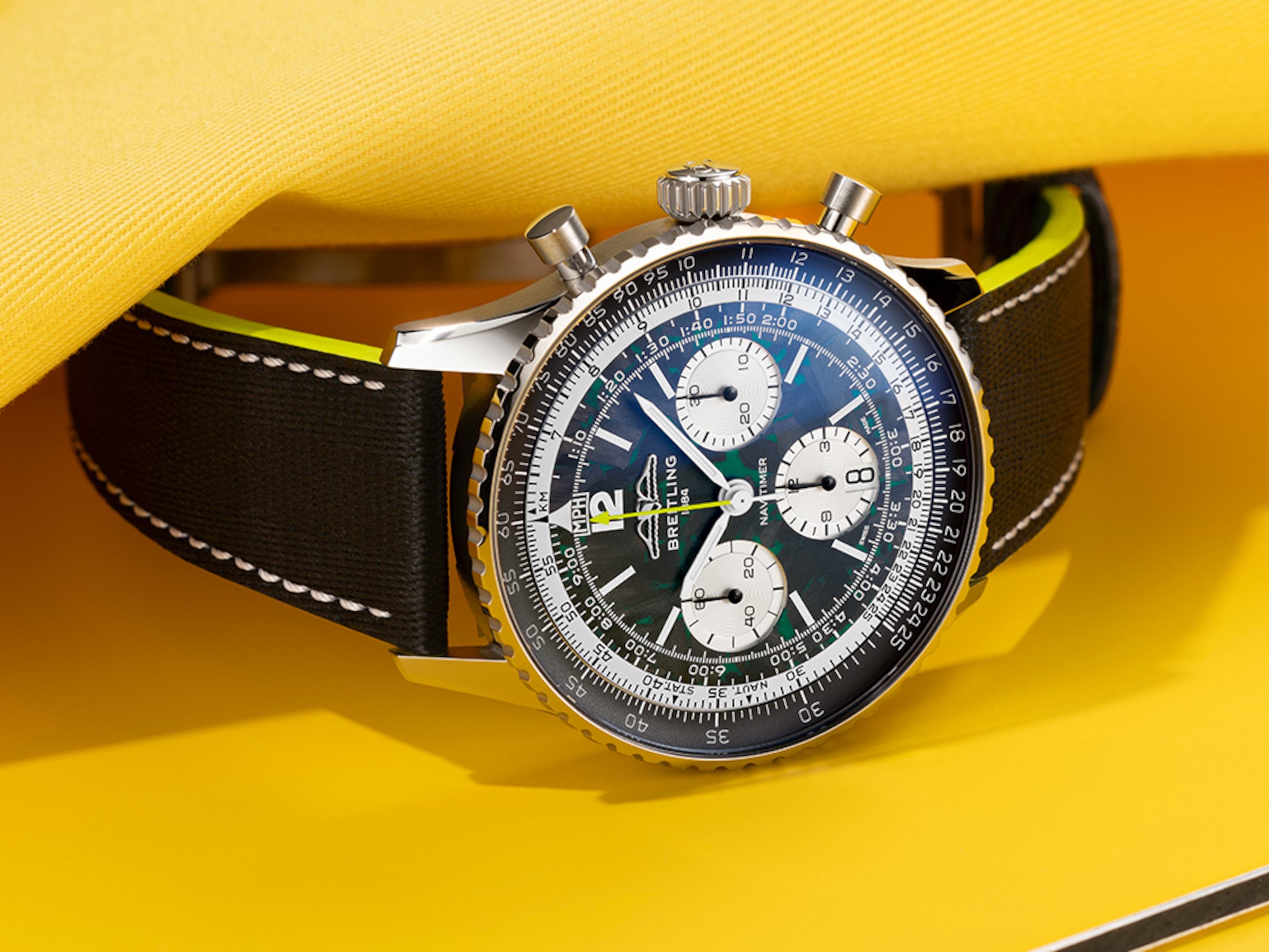 Navitimer mit hellblauem Zifferblatt und Navitimer mit einem schwarzen Zifferblatt auf einem Tisch.