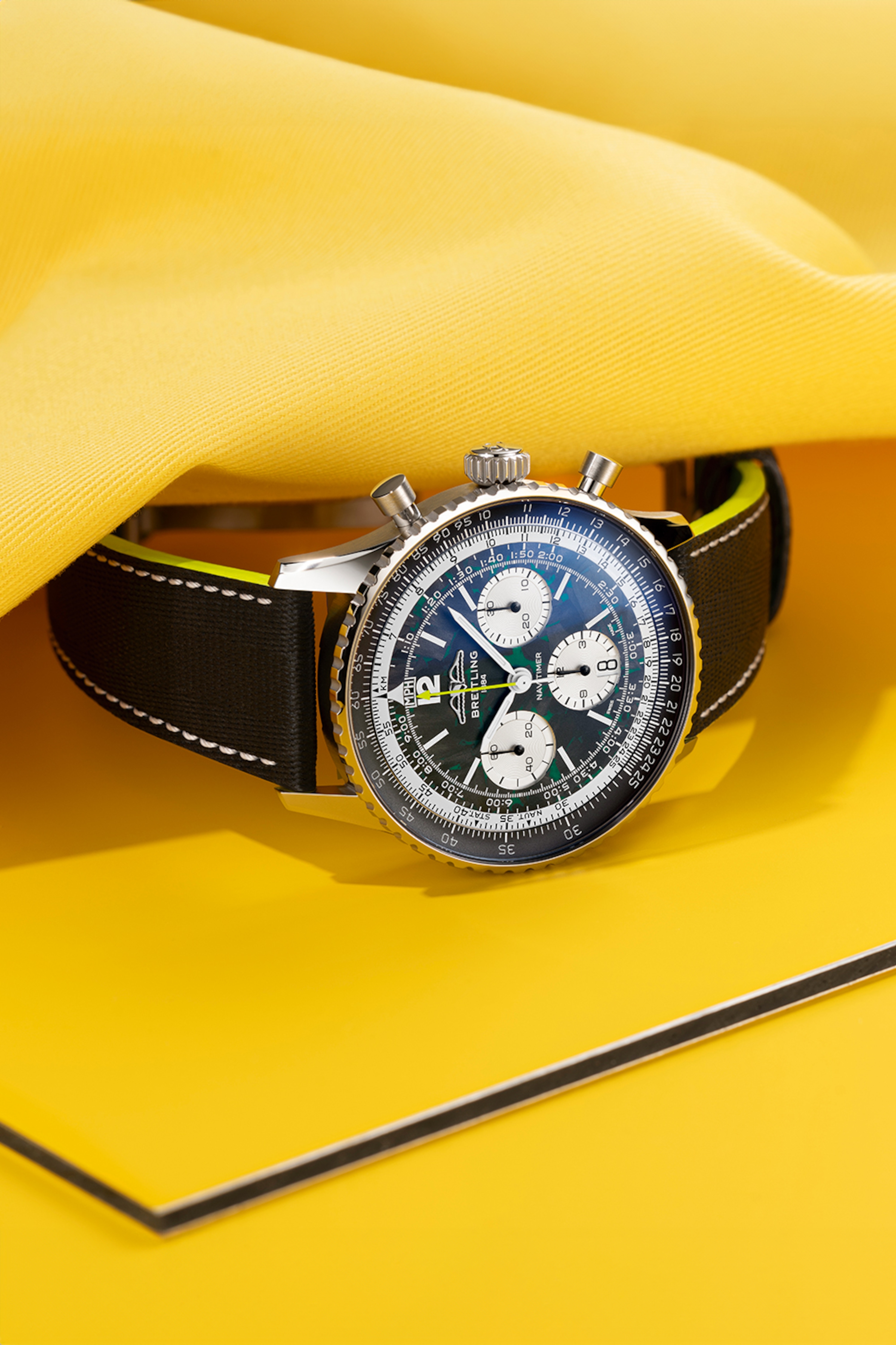 Navitimer mit hellblauem Zifferblatt und Navitimer mit einem schwarzen Zifferblatt auf einem Tisch.