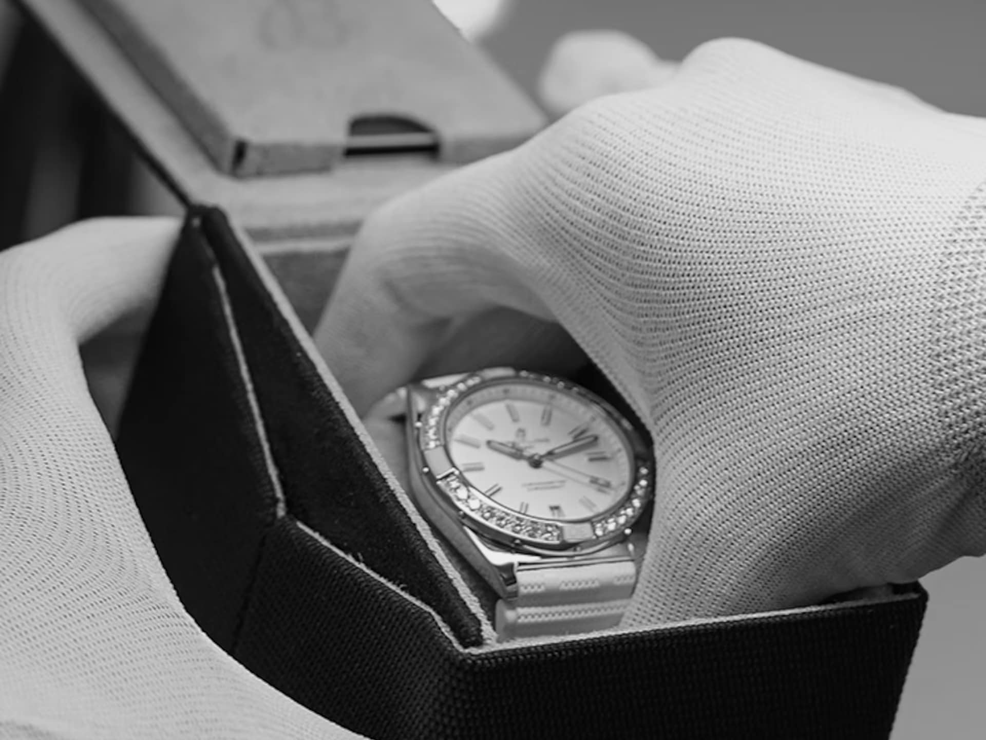 Carefully and with gloves on, a Breitling watch is taken out of its packaging.