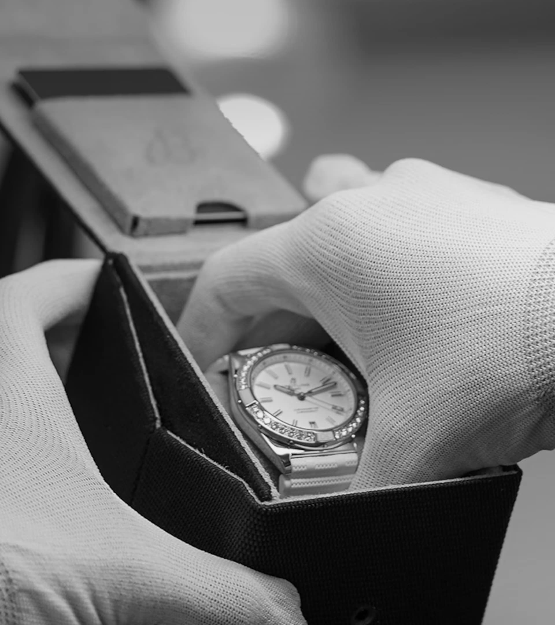 Carefully and with gloves on, a Breitling watch is taken out of its packaging.
