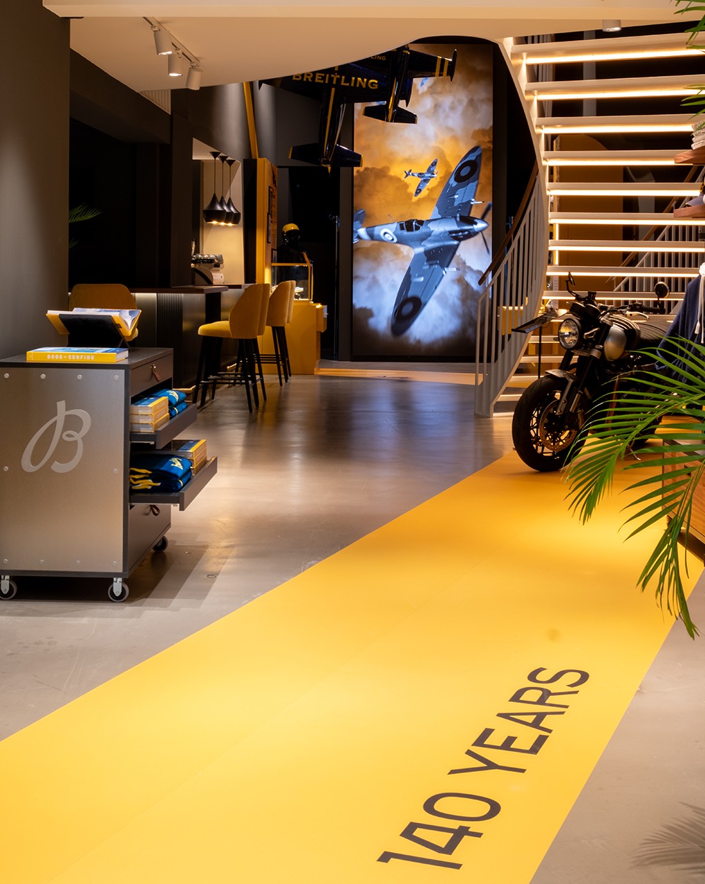 {generated} Elegantly lit Breitling space showcasing aviation artwork, branded displays, and a striking yellow 140 Years walkway.