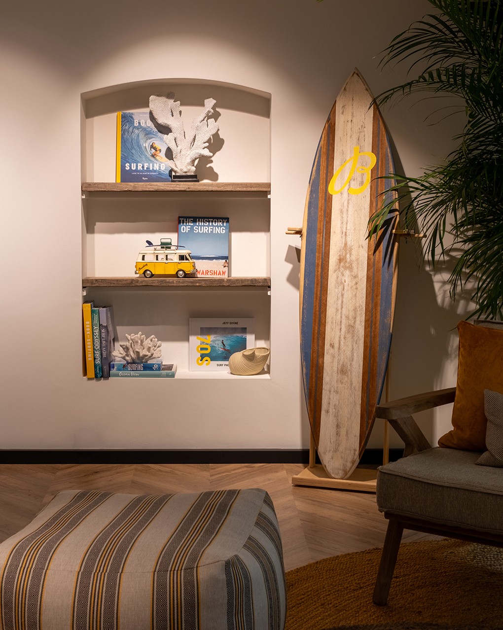 {generated} Cozy surf-themed interior with books, coral decor, and a striped surfboard featuring a yellow Breitling B logo by the shelf.