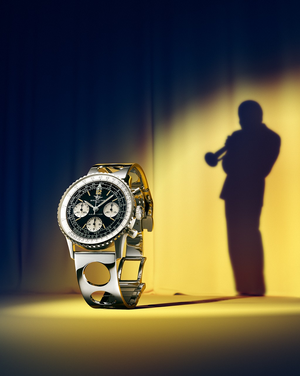 {generated} Breitling Navitimer chronograph with steel bracelet beside a trumpeter silhouette under stage lighting