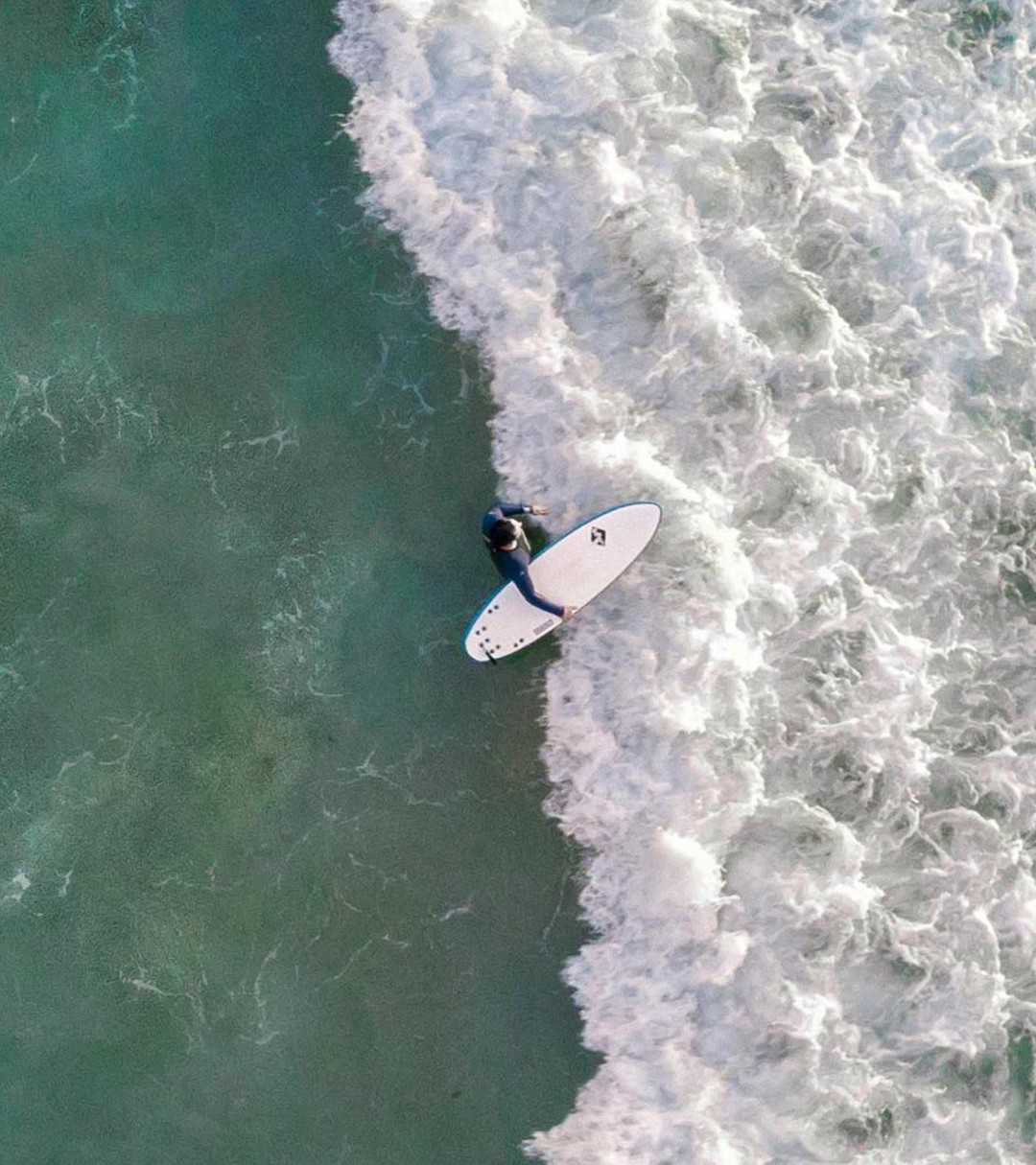 {generated} 衝浪者於翠綠海面與白浪間前行，展現Breitling對海洋永續承諾。