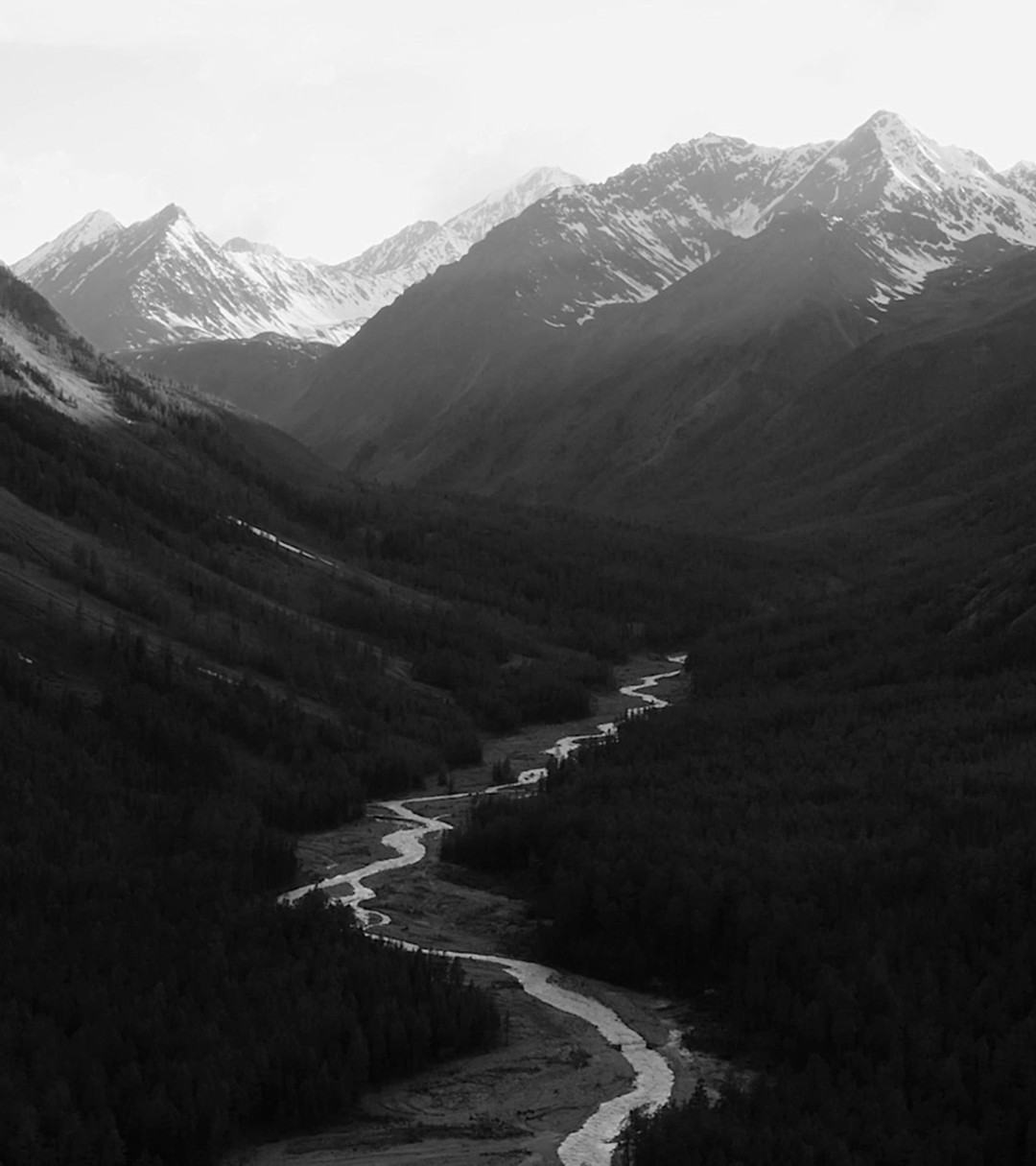 {generated} Expansive mountain valley and winding river highlighting nature’s scale and Breitling’s commitment to sustainability.
