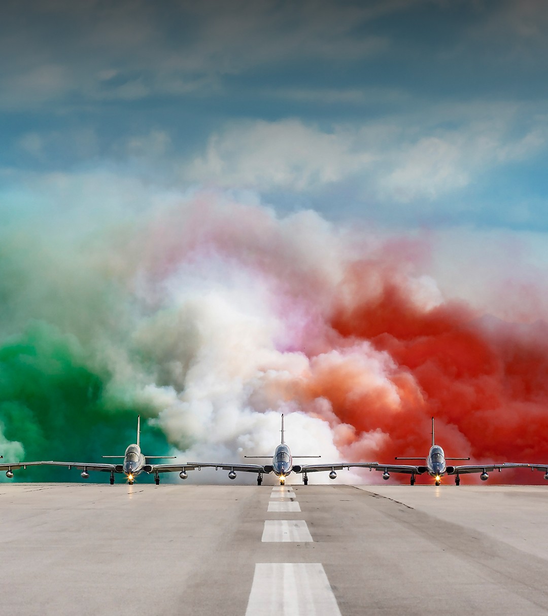 {generated} Frecce Tricoloriのジェット機が緑白赤の煙に包まれ滑走路を進み、Breitlingの航空への伝統を感じさせる。