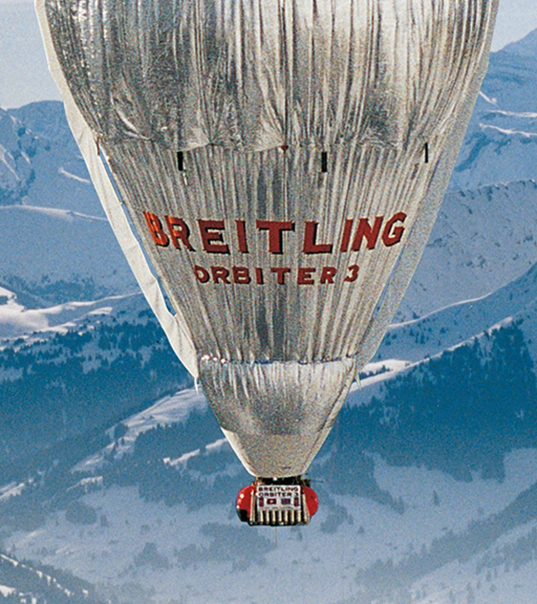 {generated} Il pallone Breitling Orbiter 3 sorvola le Alpi innevate, richiamando la spedizione pionieristica di Bertrand Piccard