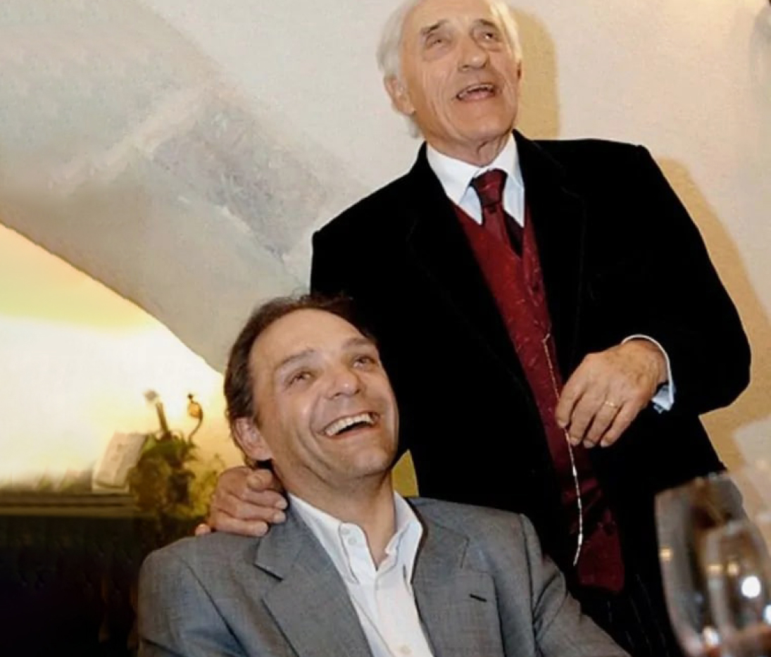 {generated} 兩位身著正裝的男子在1994年的雅緻聚會中於暖色燈光下共享寧靜時刻。