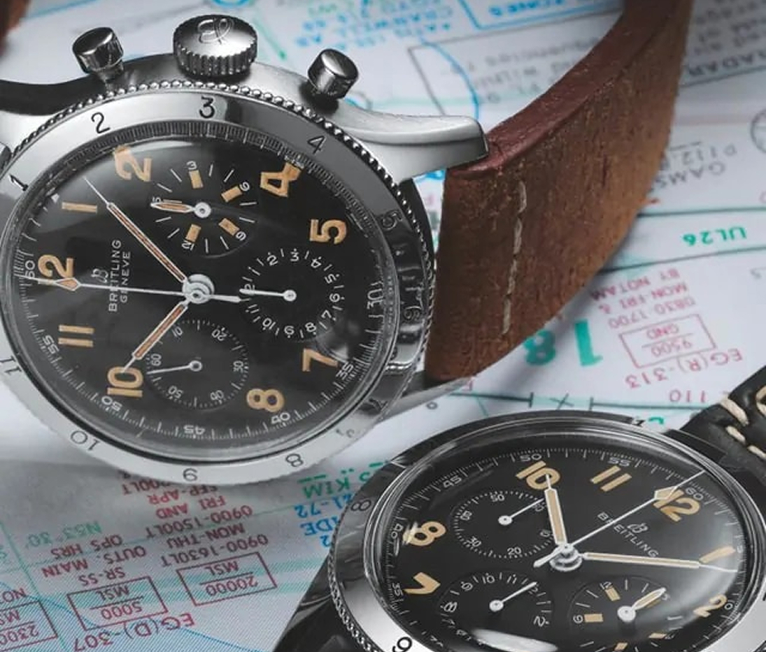 {generated} Due cronografi Breitling con quadranti neri e cinturini vintage in pelle appoggiati su schede tecniche aeronautiche