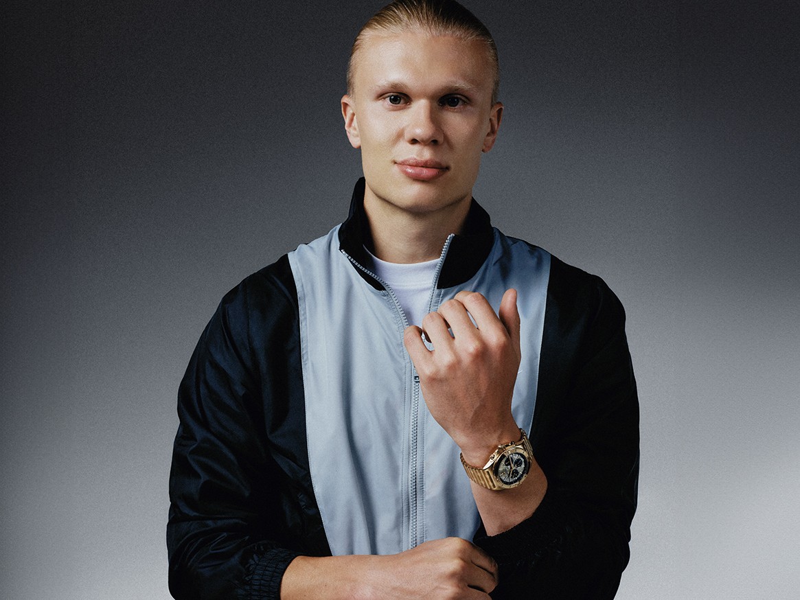 {generated} Erling Haaland figure in sporty jacket showcasing a Breitling watch on his wrist against a clean monochrome backdrop