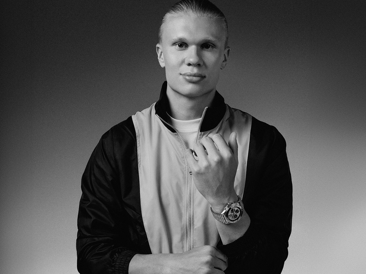 {generated} Erling Haaland figure in sporty jacket showcasing a Breitling watch on his wrist against a clean monochrome backdrop