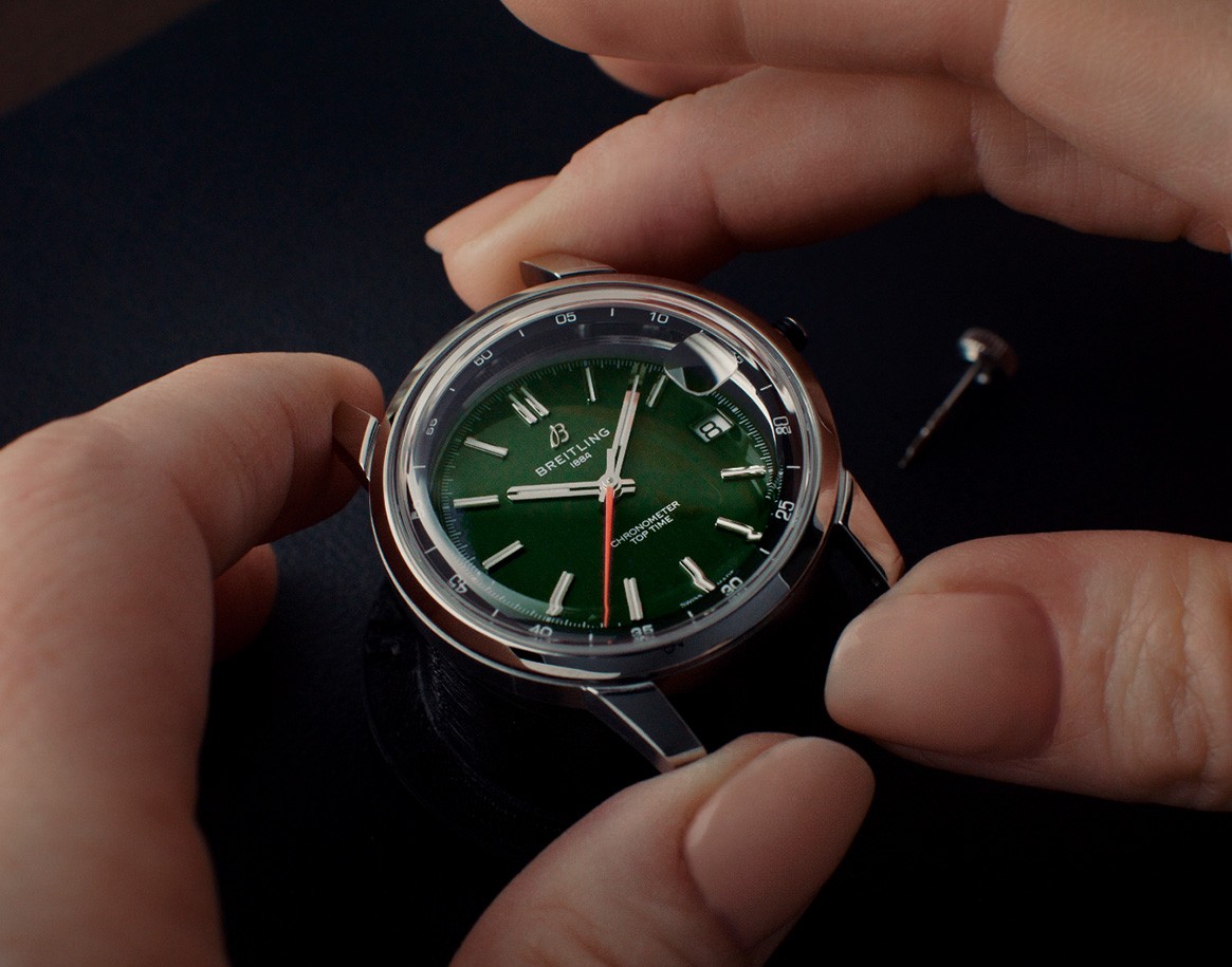 {generated} Hands carefully assembling a Breitling watch with a green dial, showcasing refined craftsmanship and precise watchmaking.