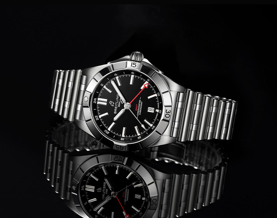 {generated} Breitling Chronomat GMT in polished steel with black dial and red GMT hand displayed against a reflective dark surface