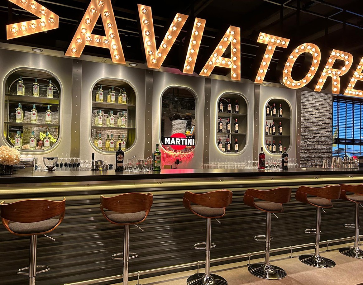 {generated} Vivace Martini bar con insegne luminose e sgabelli moderni che richiamano lo spirito dinamico della Breitling Top Time.