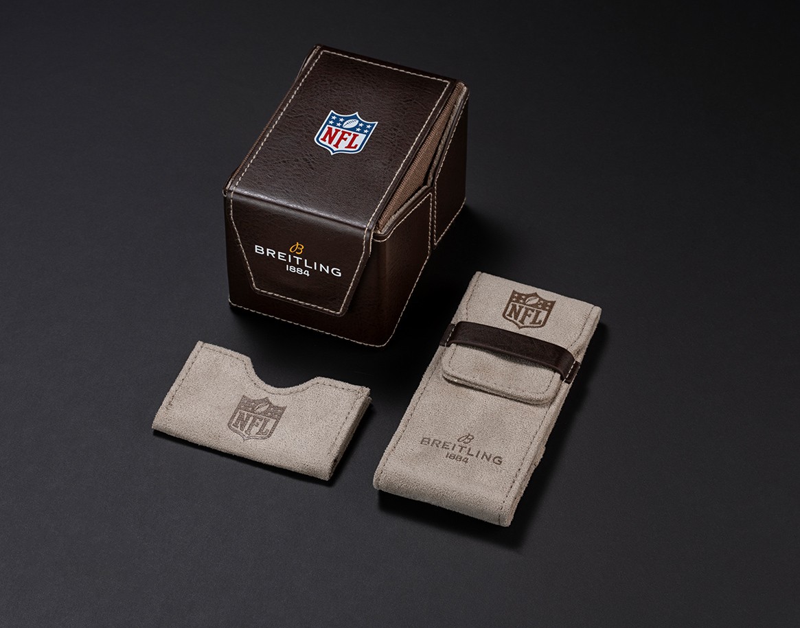 {generated} 穿紅色NFL球衣的球迷高舉球隊旗幟，在明亮天空下展示百年靈NFL球隊特別版腕錶。