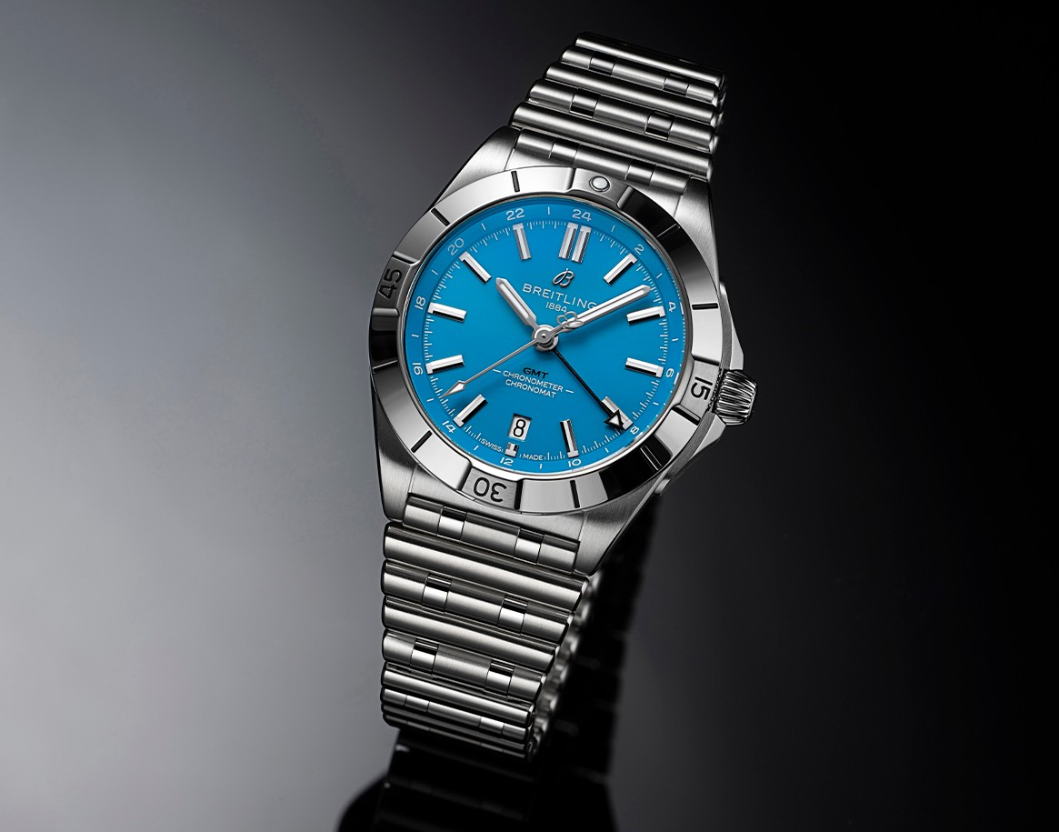 {generated} Breitling Chronomat GMT以卡羅萊納黑豹藍色錶盤與鋼錶鏈呈現在深色反光表面