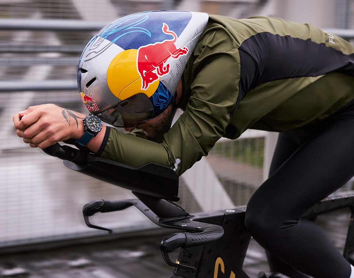 {generated} Sam Laidlow cycling in an aero stance with a Breitling watch visible on his wrist as he powers forward on a streamlined bike