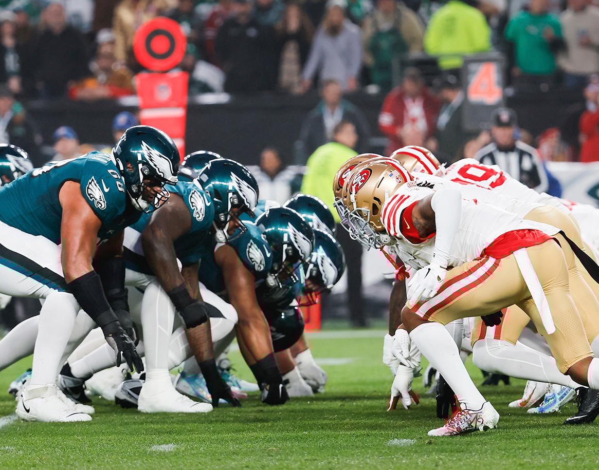 {generated} 老鷹隊與49人隊球員在開球前列陣對峙，呈現百年靈與兩支NFL球隊的合作關係。