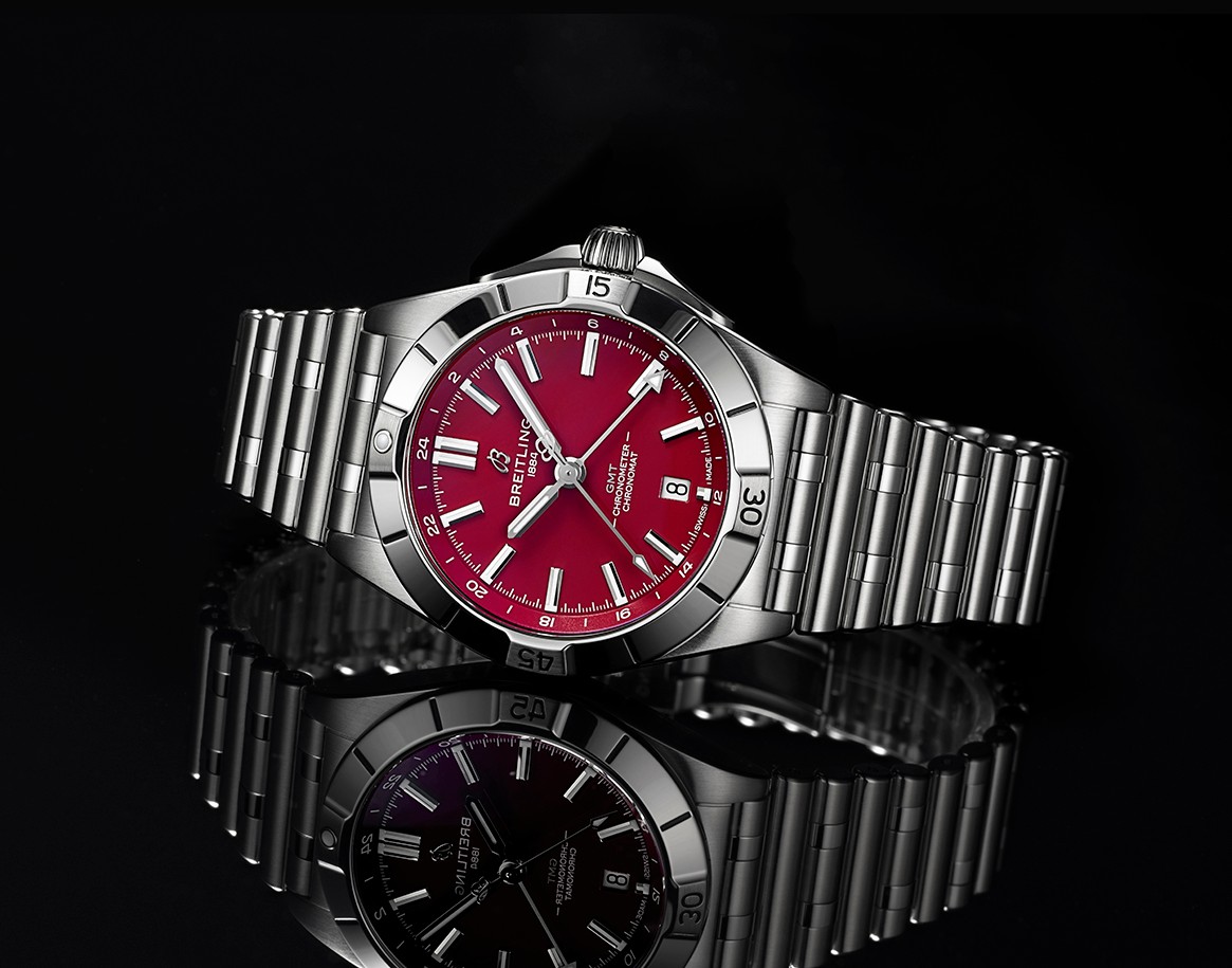 {generated} Breitling Chronomat GMT with a bold red dial and steel bracelet displayed against a dark reflective surface