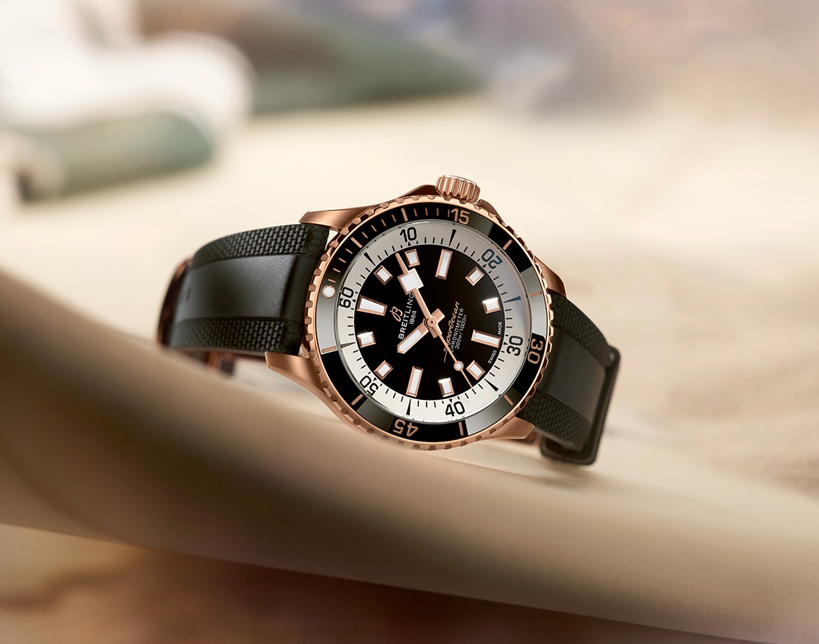 {generated} 暖かな光の中で輝くBreitling Superocean。黒いダイヤルとゴールド調ケース、質感ある黒いラバーストラップを際立たせる。