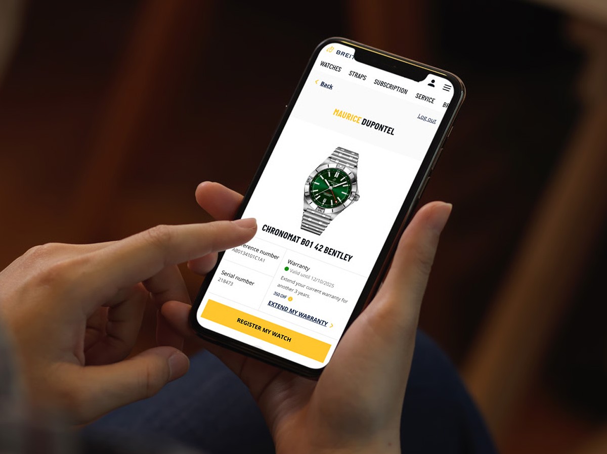 {generated} Hands hold a phone showing a Breitling Chronomat B01 42 Bentley as a user selects the Get My Breitling NFT option