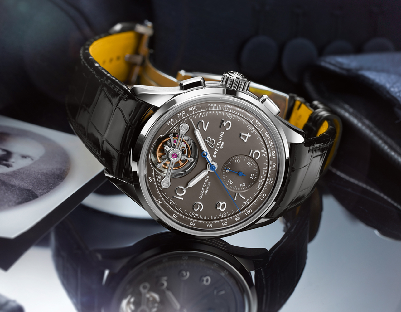 {generated} Breitling Premier watch with grey dial, open-heart detail and black leather strap displayed on reflective surface