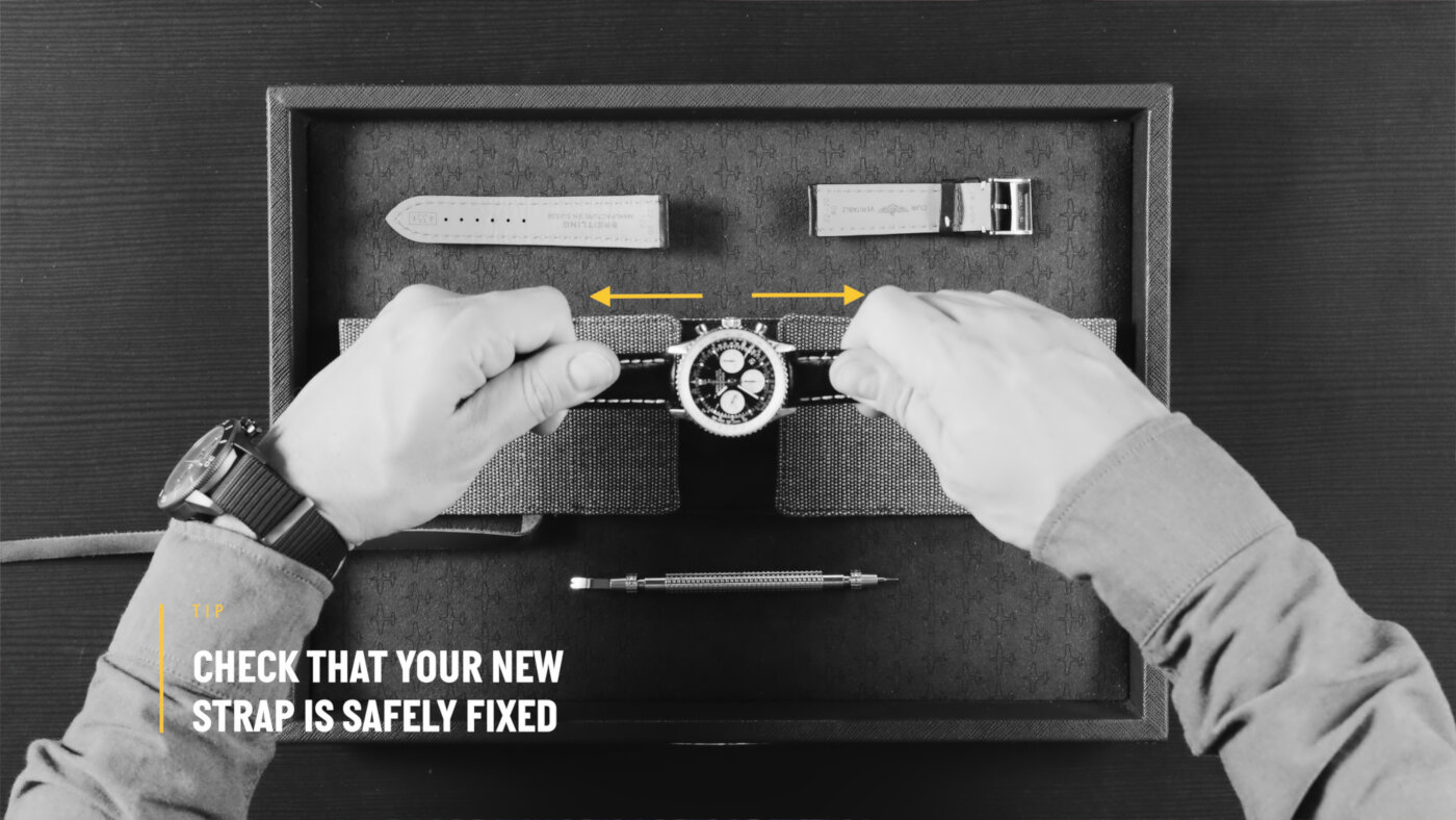 {generated} Руки проверяют закреплённый ремешок Breitling над мягкой подставкой, сверху аккуратно разложены инструменты и ремешки.