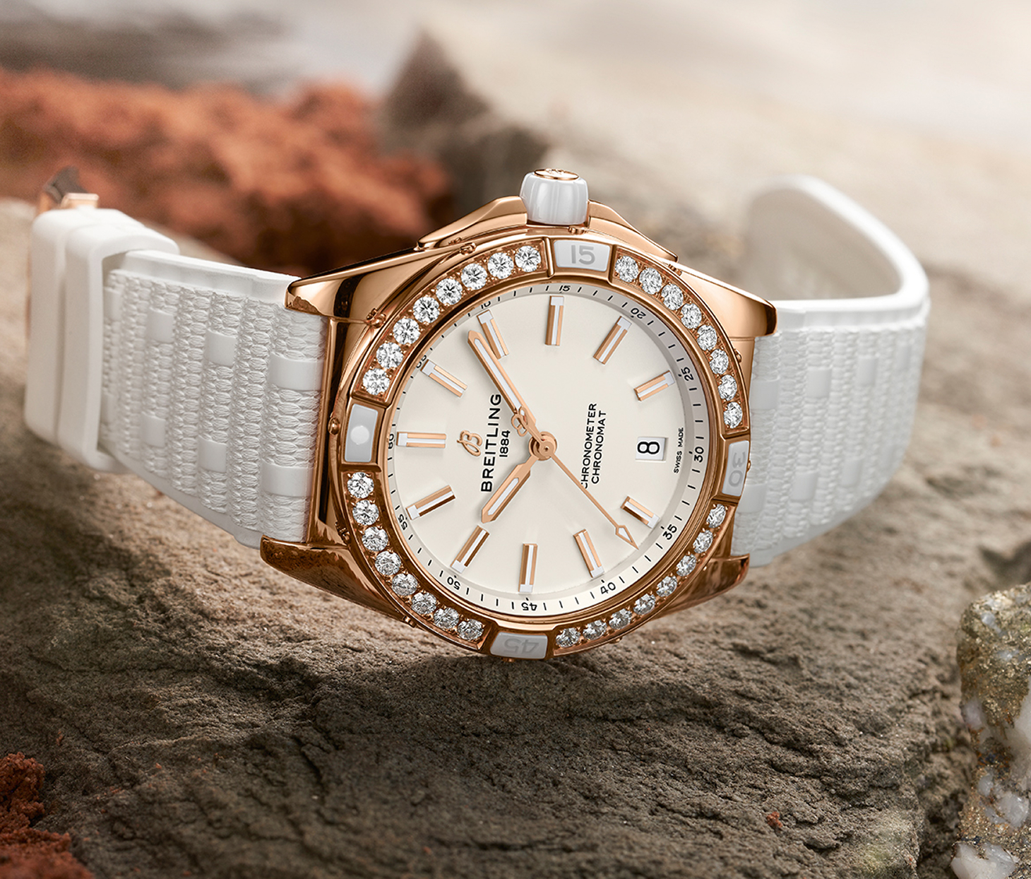 {generated} Breitling Chronomat su pietra testurizzata con cassa in oro rosa, lunetta con diamanti e cinturino in gomma bianca