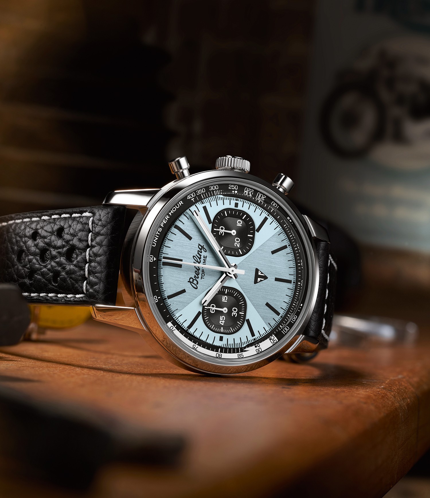 {generated} Montre Breitling Top Time Triumph au cadran bleu glacé et compteurs noirs posée sur une surface en bois sous une lumière chaude