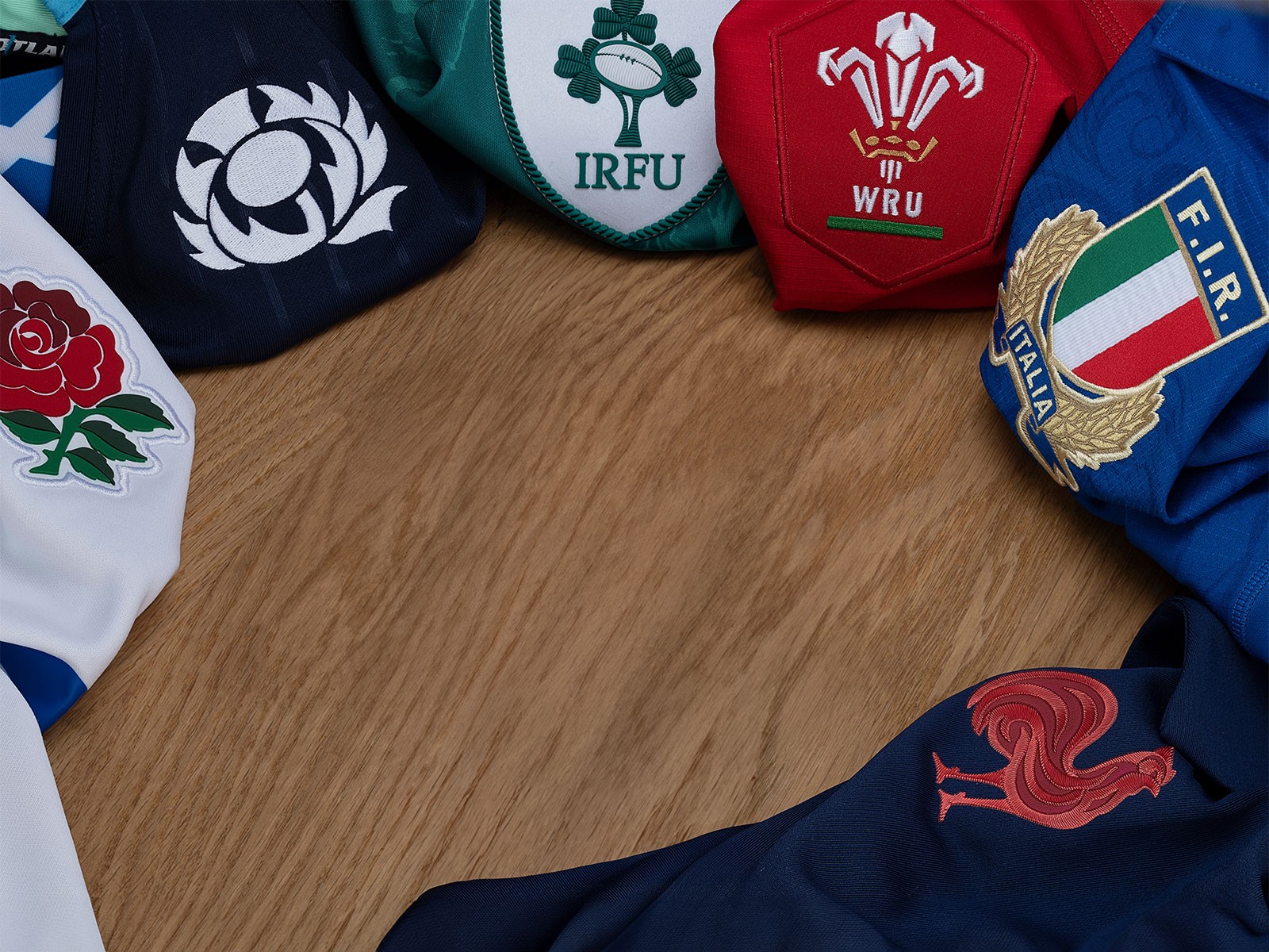 {generated} Six Nations rugby jerseys encircle a wooden surface, displaying each team’s emblem in a unified competitive layout