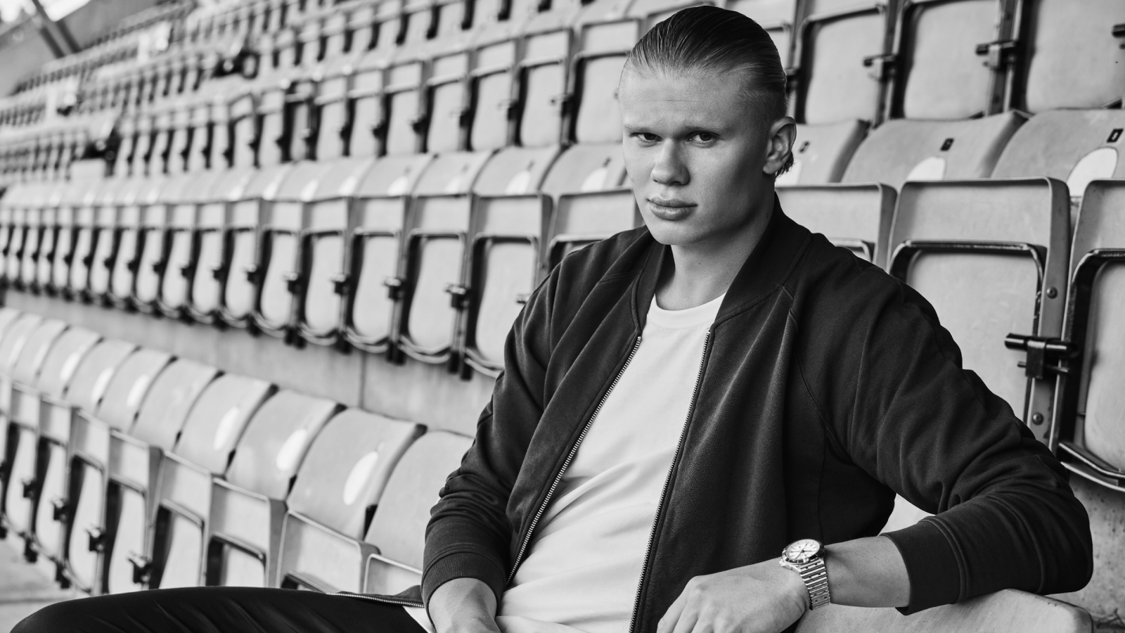 {generated} 男子坐在空蕩看台上佩戴百年靈腕錶，展現適用於140周年訂閱主題的格調。