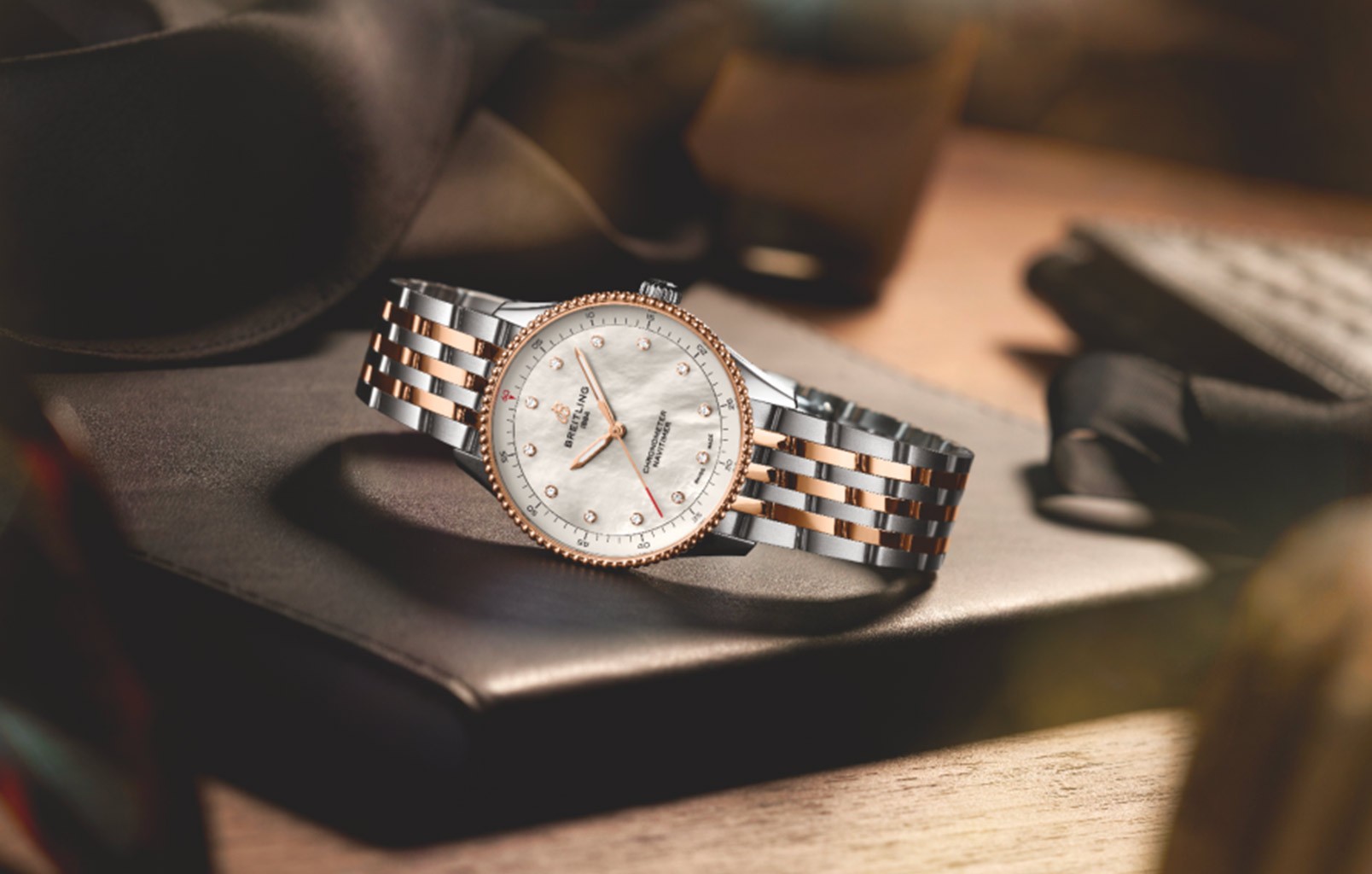 {generated} Breitling珍珠母貝錶盤與鑽石時標腕錶置於柔軟布料上，展現溫暖且雅緻的氛圍