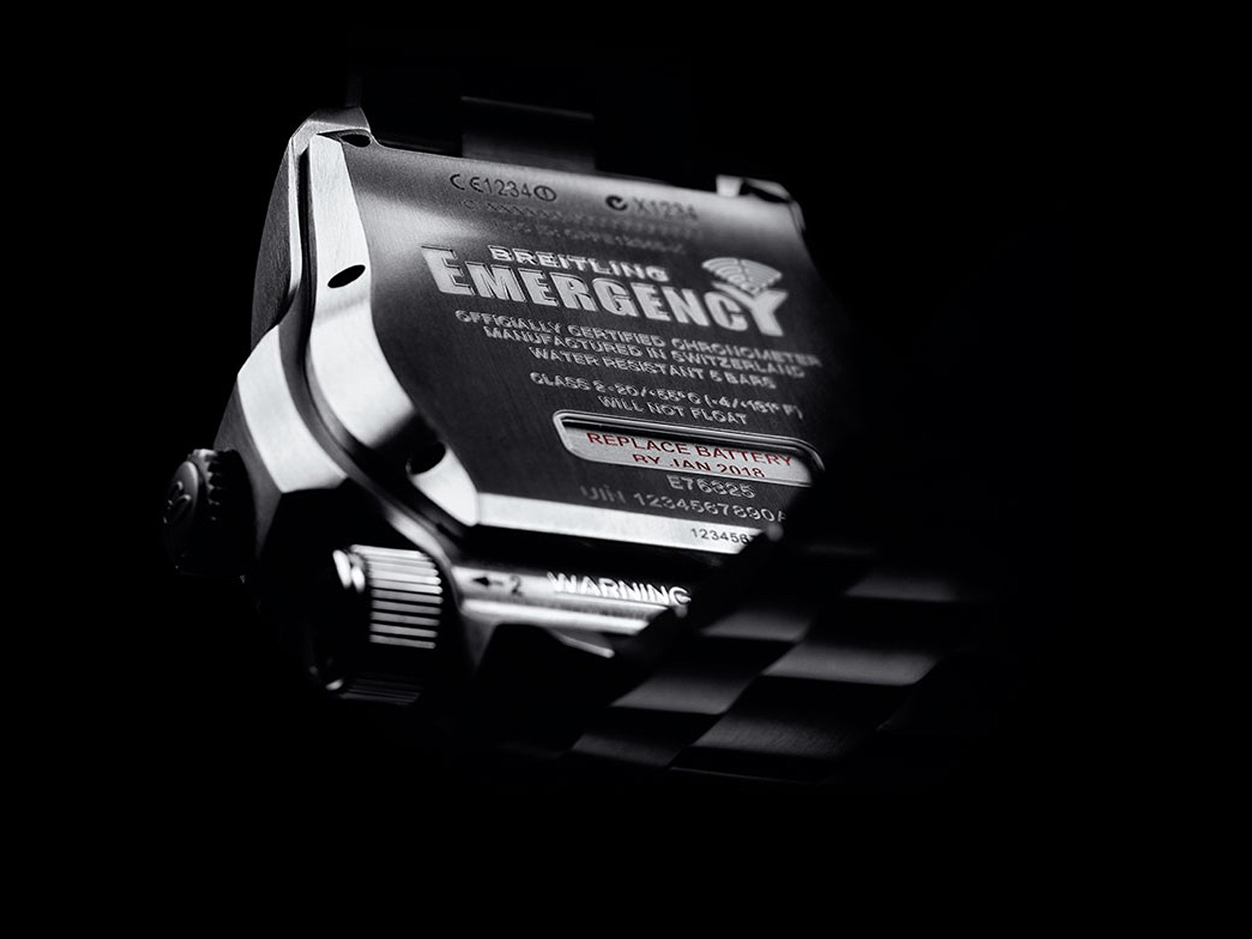 {generated} Close-up of the Breitling Emergency caseback highlighting engraved specifications and functional emergency components.