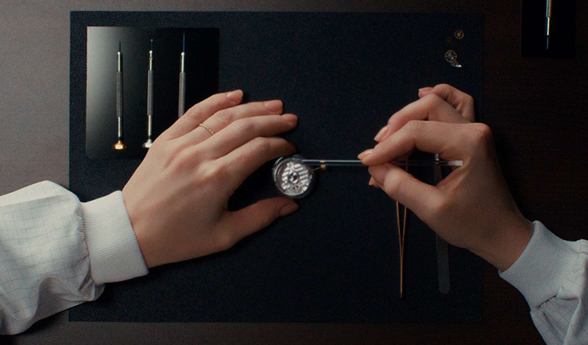 {generated} Manos que revisan un movimiento Breitling con herramientas de precisión sobre un banco oscuro, mostrando atención experta