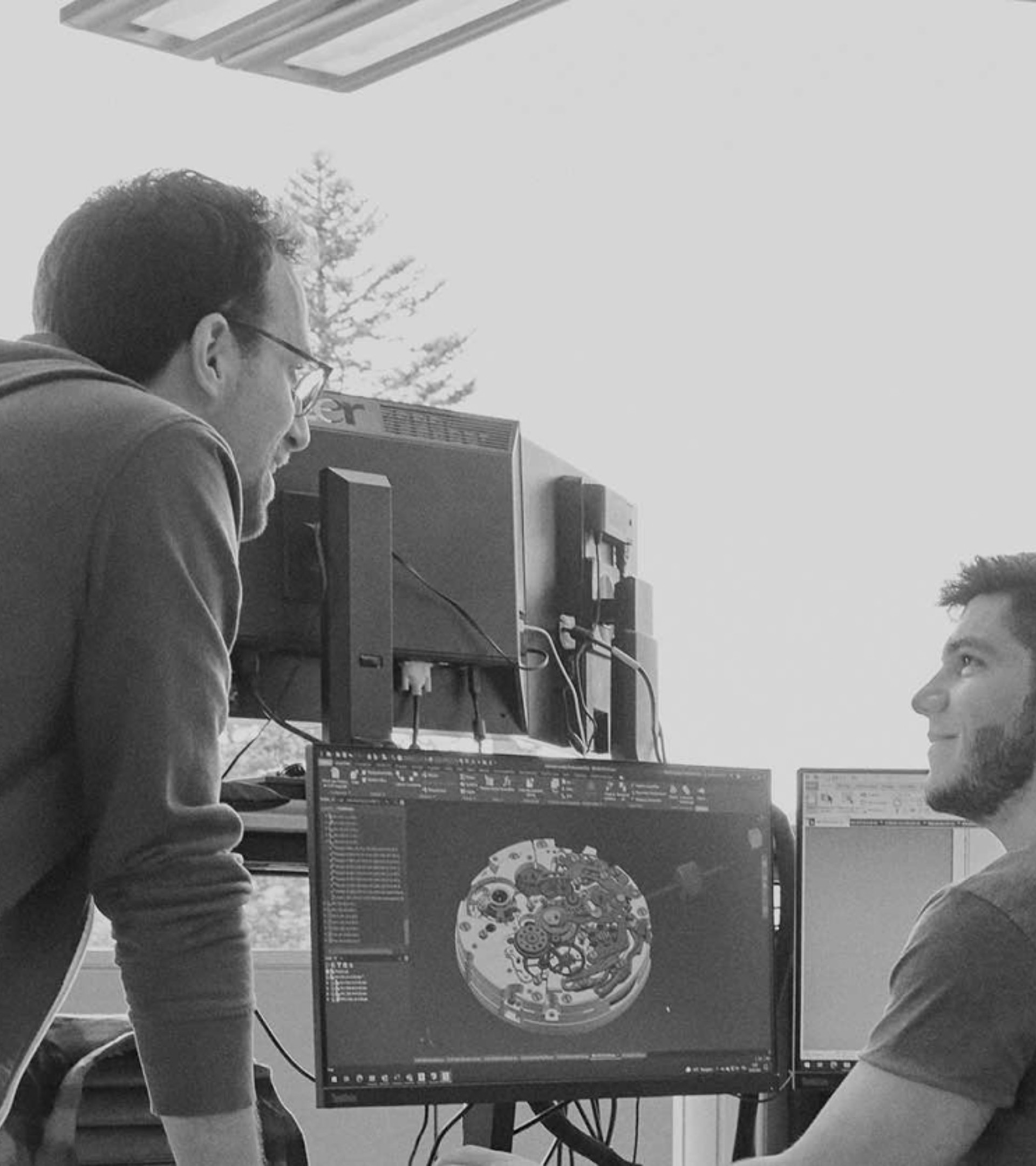 {generated} Engineers examine intricate digital schematics across several screens within a bright Breitling research and development space