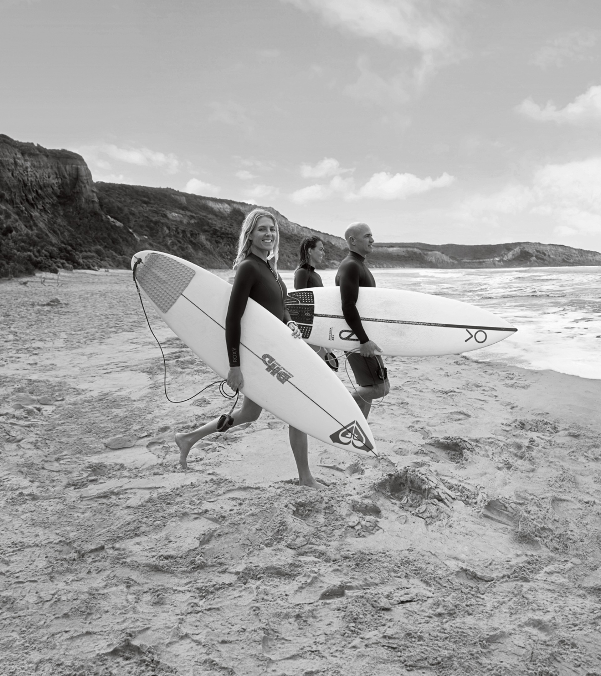 {generated} Tres surfistas con tablas esperan en una costa tranquila, transmitiendo un ambiente aventurero ideal para inscripciones al boletín.
