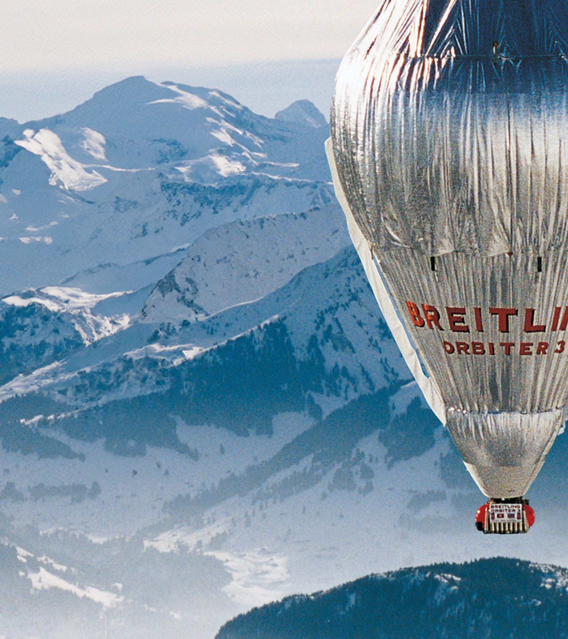 {generated} Breitling Orbiter 3 hot-air balloon gliding above expansive snowy mountain peaks, highlighting adventurous spirit.