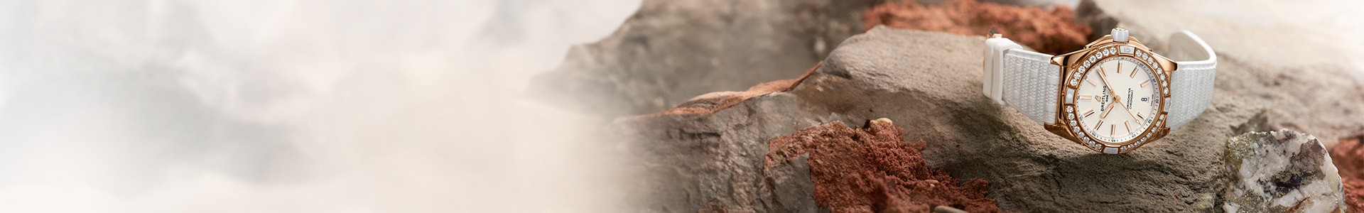 {generated} Breitling Origins watch with white strap and diamond-set bezel resting on rugged stone amid soft mist.