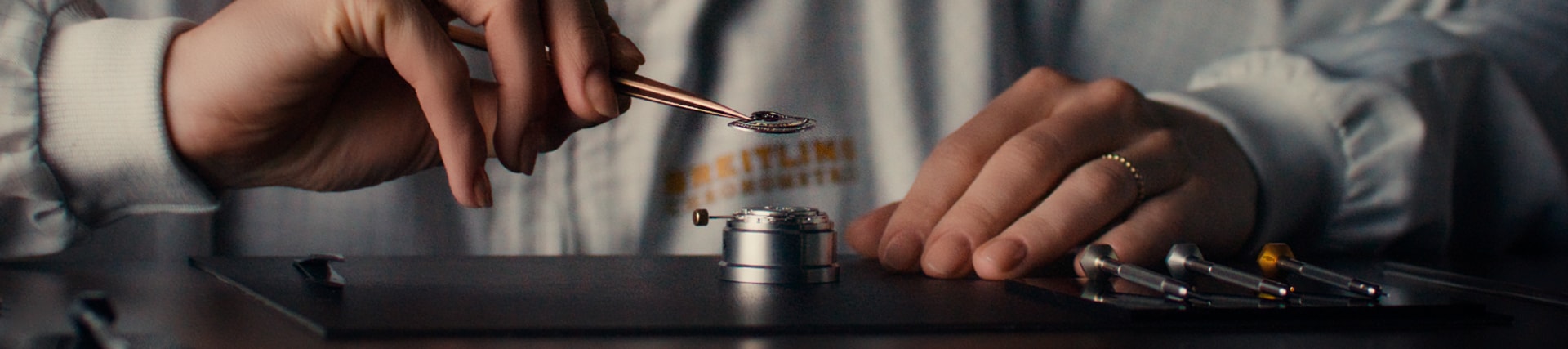{generated} A watchmaker in a Breitling coat carefully adjusts a movement with precision tools, highlighting meticulous service work