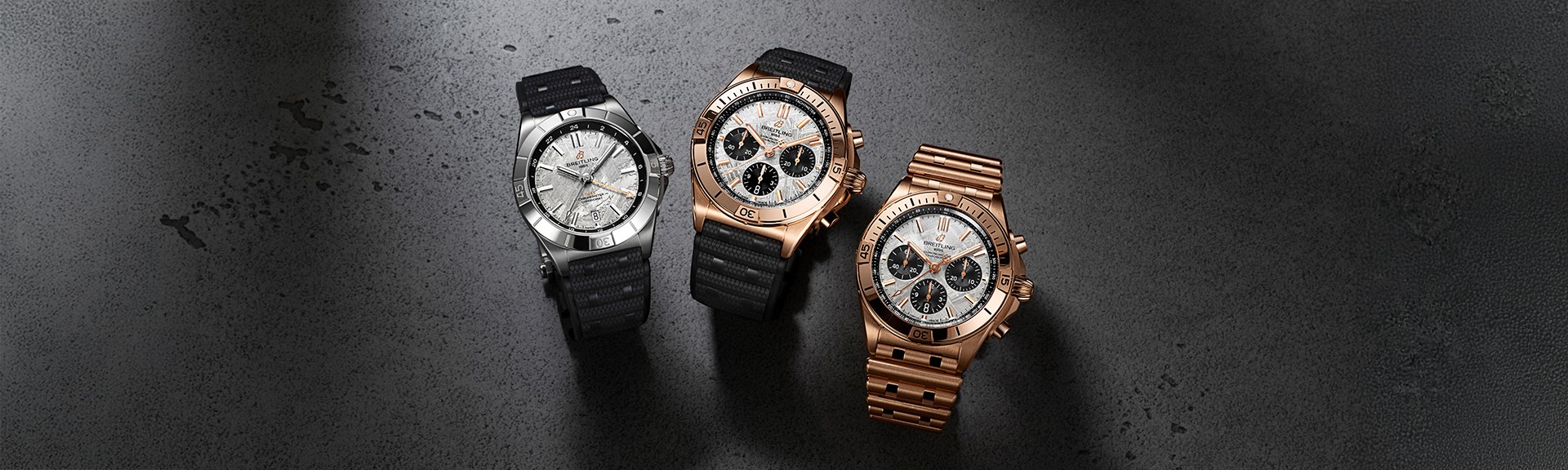 {generated} Breitling Chronomat Erling Haaland モデルが暗い面に並び、スチールとローズゴールドの仕上げを強調