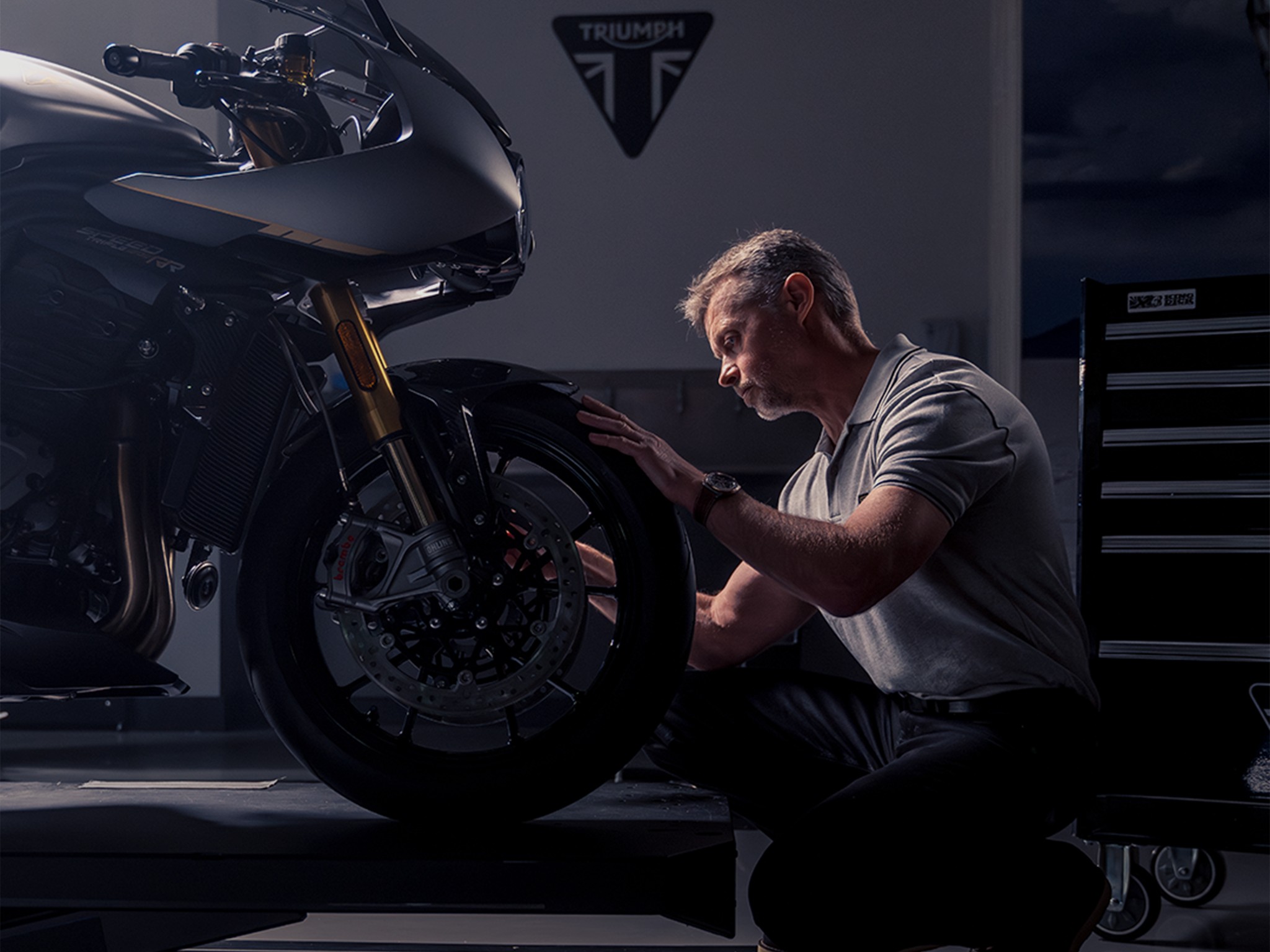 {generated} A technician inspects a Triumph motorcycle in a workshop, reflecting the precision central to the Breitling partnership.