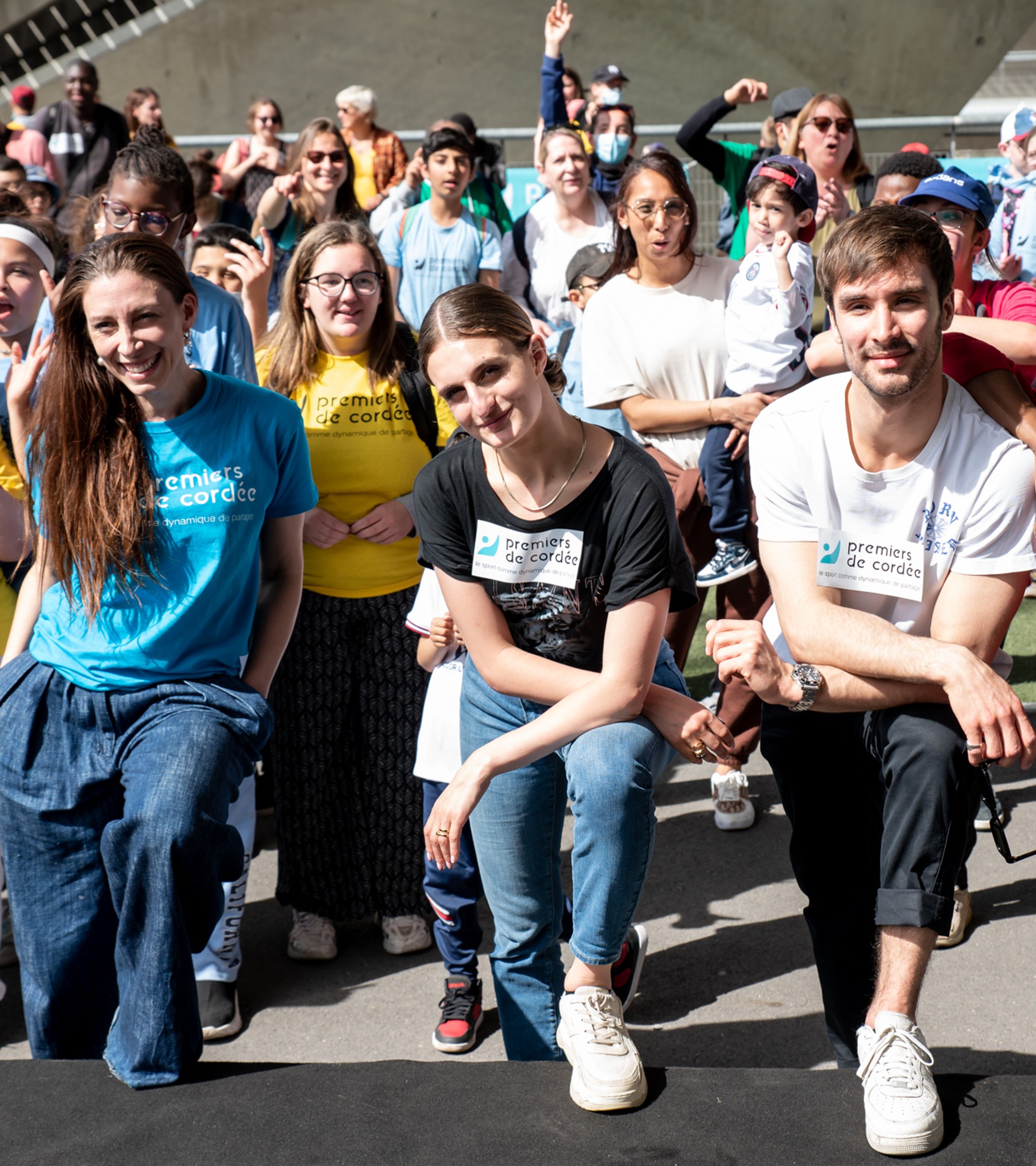 {generated} Enfants et adultes rassemblés en plein air en tee‑shirts colorés Premiers de Cordée lors d’un événement communautaire animé