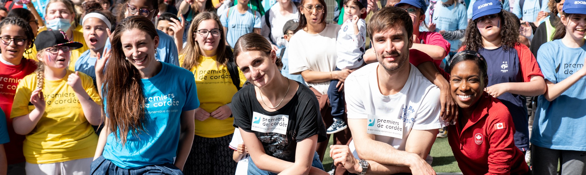 {generated} Enfants et adultes rassemblés en plein air en tee‑shirts colorés Premiers de Cordée lors d’un événement communautaire animé