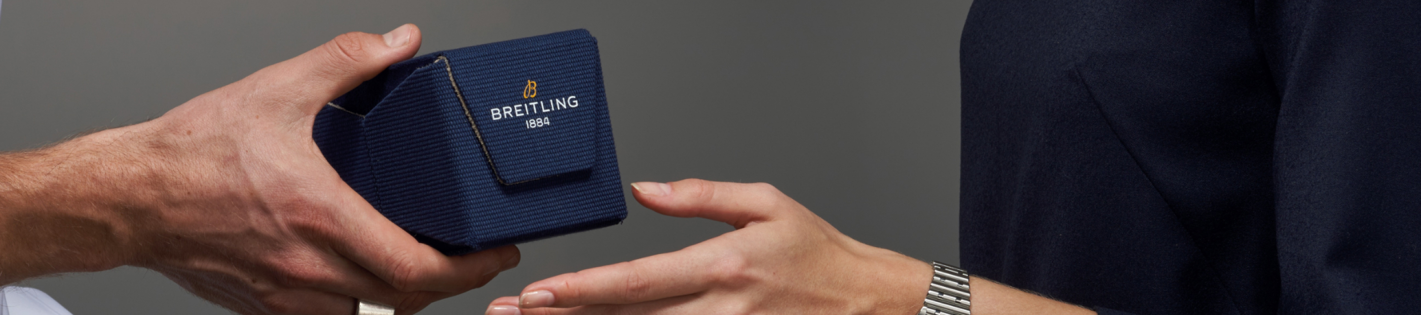 {generated} Hände tauschen eine blaue Breitling Box und vermitteln hochwertigen Service sowie edle Präsentation in ruhiger Szenerie