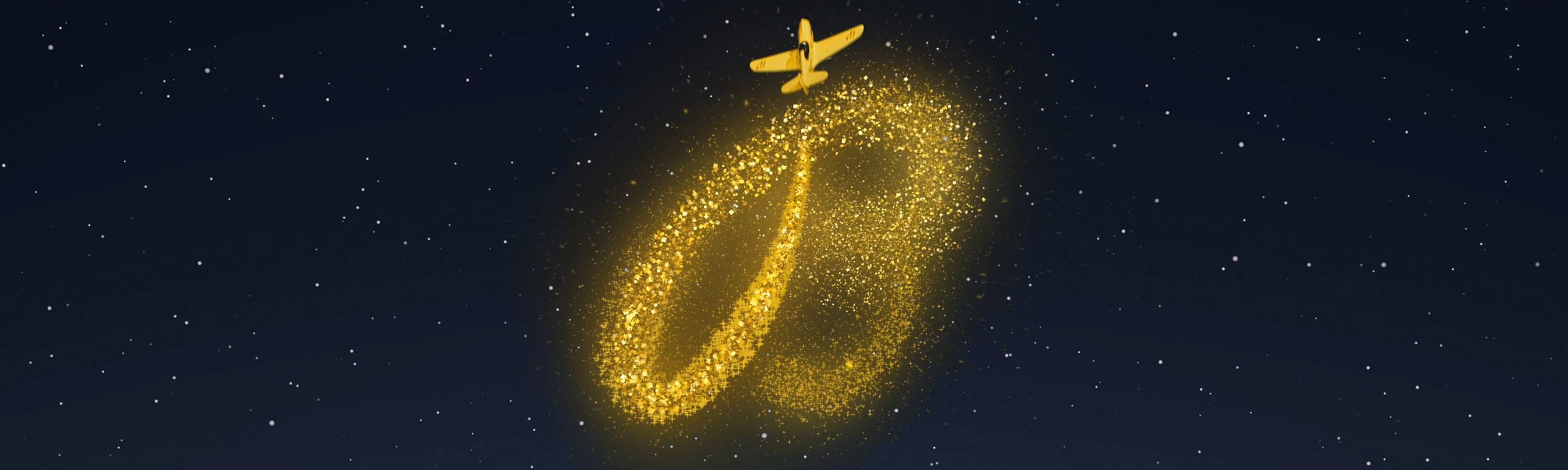 Gloved hands holding a yellow gift box with gold ribbon on a yellow surface, surrounded by wrapping tools and holiday decorations.