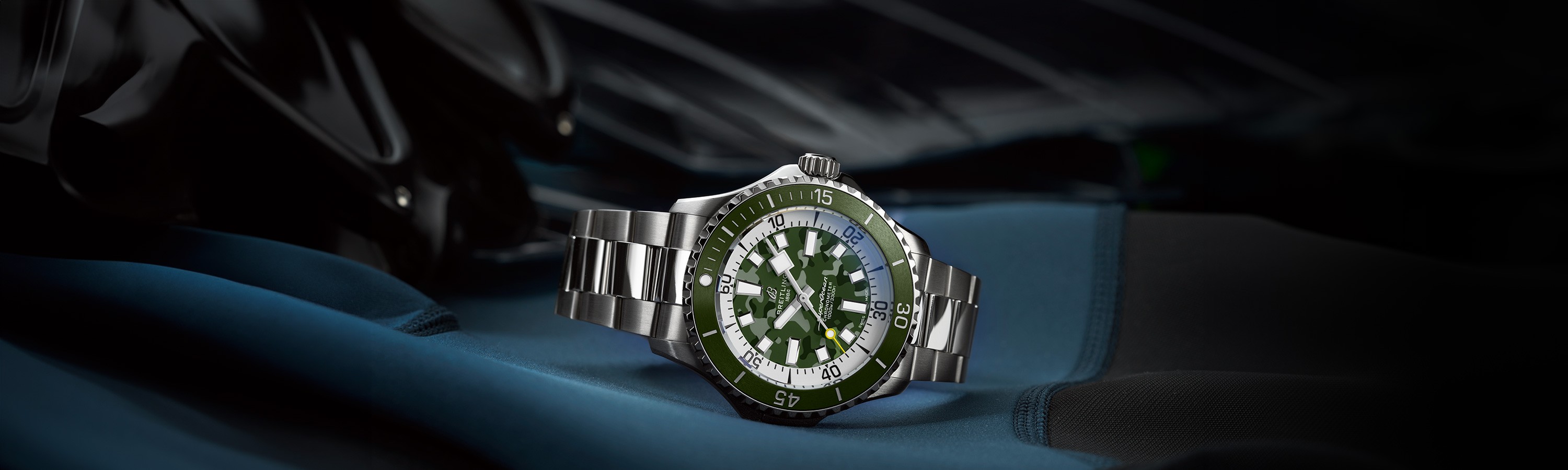 {generated} Breitling鈦金屬腕錶以綠色迷彩錶盤與鋼錶鏈置於深色裝備上，展現其堅固而精準的特質。