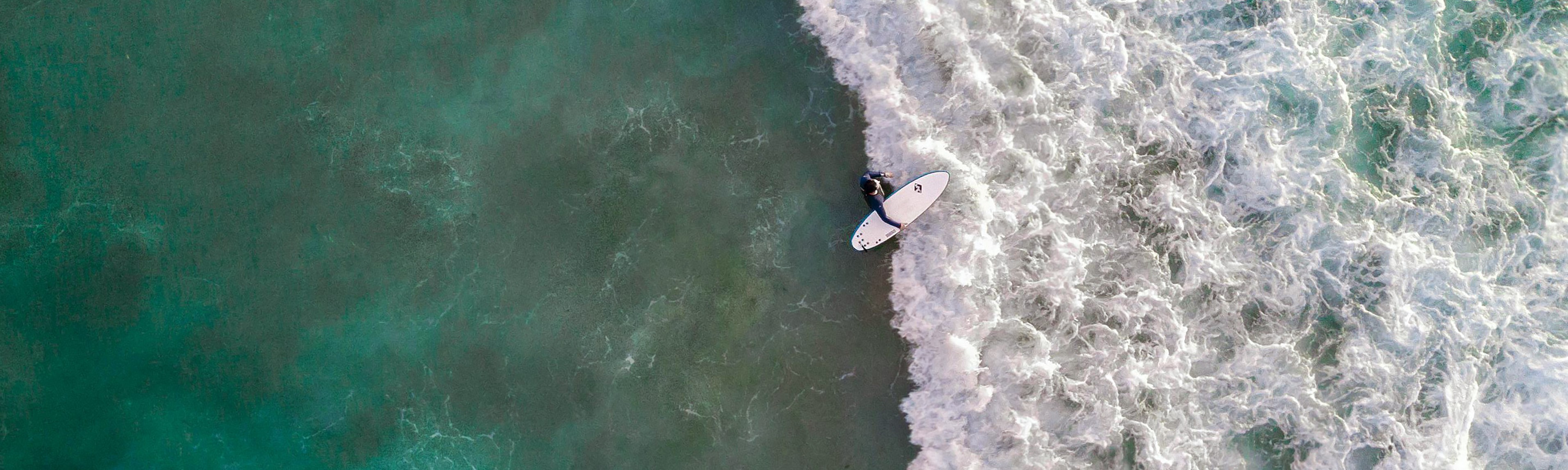 {generated} 衝浪者於翠綠海面與白浪間前行，展現Breitling對海洋永續承諾。